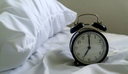 Close-up of alarm clock on bed