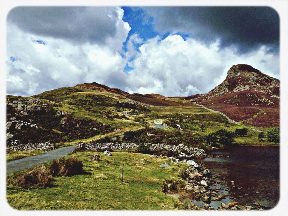 transfer print, mountain, sky, tranquil scene, scenics, auto post production filter, tranquility, cloud - sky, water, mountain range, beauty in nature, landscape, cloudy, nature, cloud, rock - object, lake, non-urban scene, grass, river