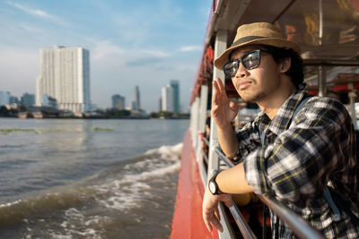 Tourist wearing hat standing in boat on river