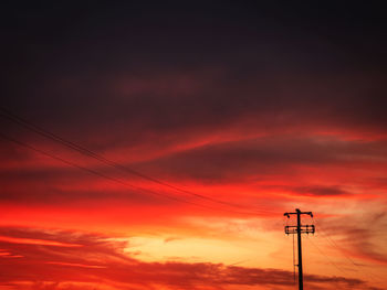 Low angle view of electricity pylon against sky during sunset