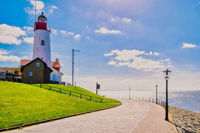 Lighthouse by sea against sky