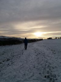 Rear view of man standing on snow covered land