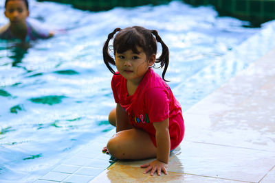 Cute girl sitting in swimming pool