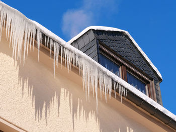 Low angle view of building against blue sky, icicles on a house 