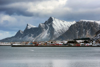 Scenic view of sea by snowcapped mountains against sky norway