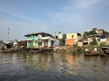 Buildings by river against sky