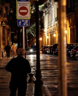 Rear view of man on city street at night