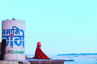 Man with text by sea against clear sky