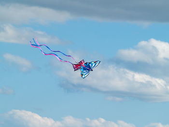 Low angle view of kites flying against blue sky