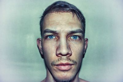 Close-up portrait of young man against colored background