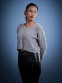 Portrait of young woman standing against blue background