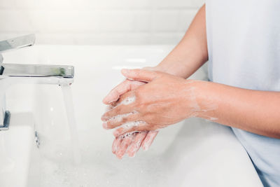 Midsection of man washing hands in sink