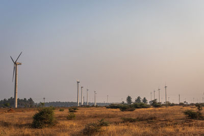 Wind turbines on field against clear sky