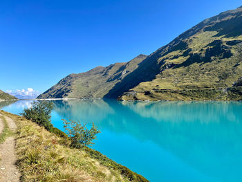 Scenic view of lake and mountains against clear blue sky