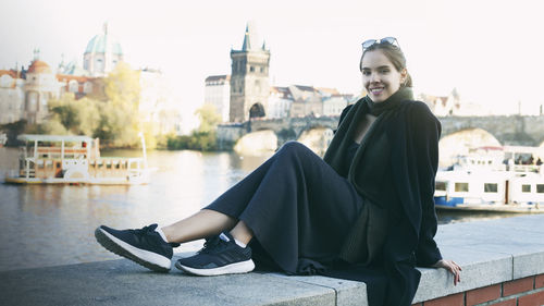 Portrait of beautiful young woman sitting in city