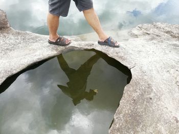 Low section of man standing on sea shore