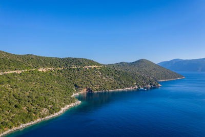 Scenic view of sea and mountains against clear blue sky