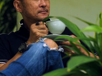 Portrait of man drinking water from plant