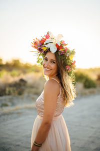 Portrait of smiling young woman standing at beach against clear sky