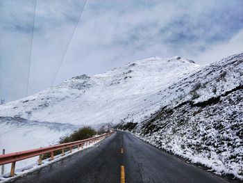 Road amidst snowcapped mountains against sky