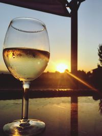 Close-up of beer glass on table against sky during sunset