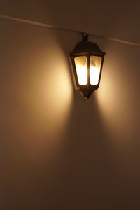 Low angle view of illuminated light bulb hanging on ceiling