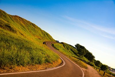 Low angle view of winding road against blue sky