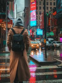 Rear view of man walking on road in rain