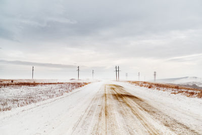 Empty road against cloudy sky in winter