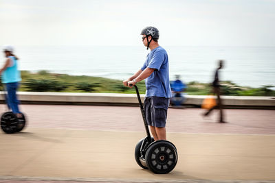 Side view of man with umbrella standing on skateboard