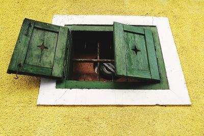 Low angle view of window on yellow wall