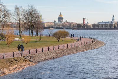 People walking on river by buildings in city