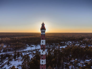 Lighthouse on the shore of the lake, illuminated by the rays of the evening sun. aerial photography