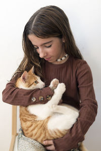 Girl carrying cat while sitting on chair