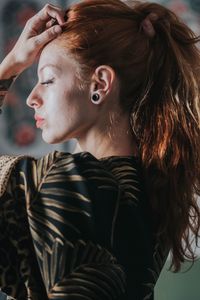 Young woman tying hair at home