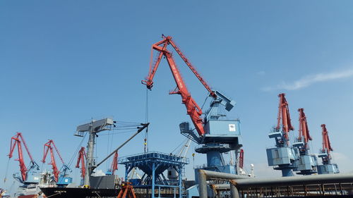 Cranes at commercial dock against clear sky