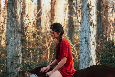 Side view of man sitting on tree trunk