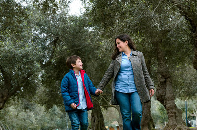 Full length of a smiling woman standing in forest