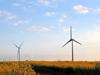 Windmills on field against sky