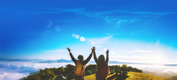 Rear view of woman with arms raised against sky