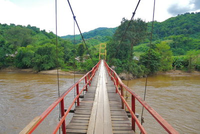 Footbridge over river against sky