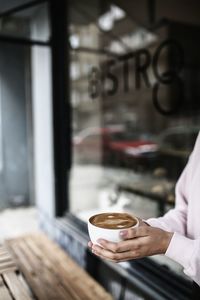 Hand holding coffee cup at cafe