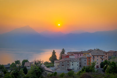 Houses in town against sky during sunset