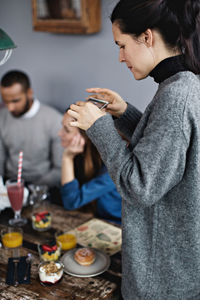 Young woman photographing food on dining table at restaurant