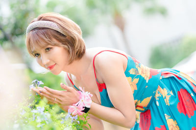 Beautiful woman smelling flowering plant at park