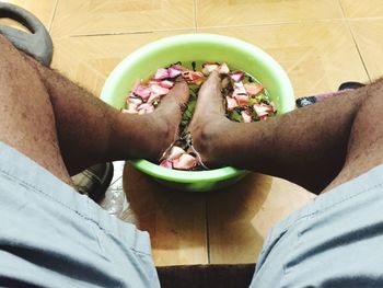 Man soaking feet in basin with water and petals