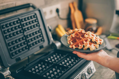 Cropped hand of woman holding waffles in plate