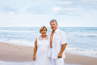 Friends standing on beach by sea against sky