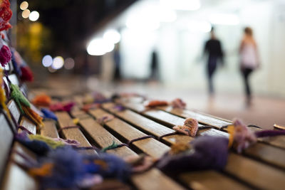 Close-up of decoration on bench with people walking on floor in background