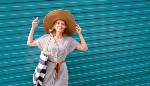 Portrait of a smiling young woman standing against blue wall